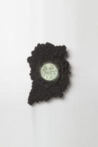 wall sconce in organic, irregular shape made of black steel with illuminated glass orb lens in center