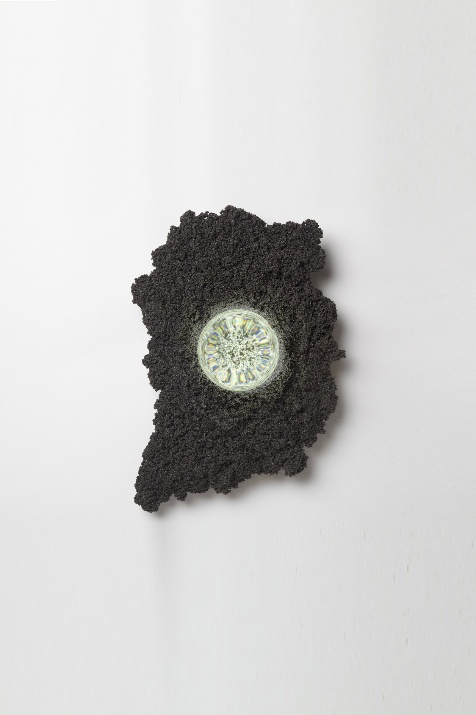 wall sconce in organic, irregular shape made of black steel with illuminated glass orb lens in center