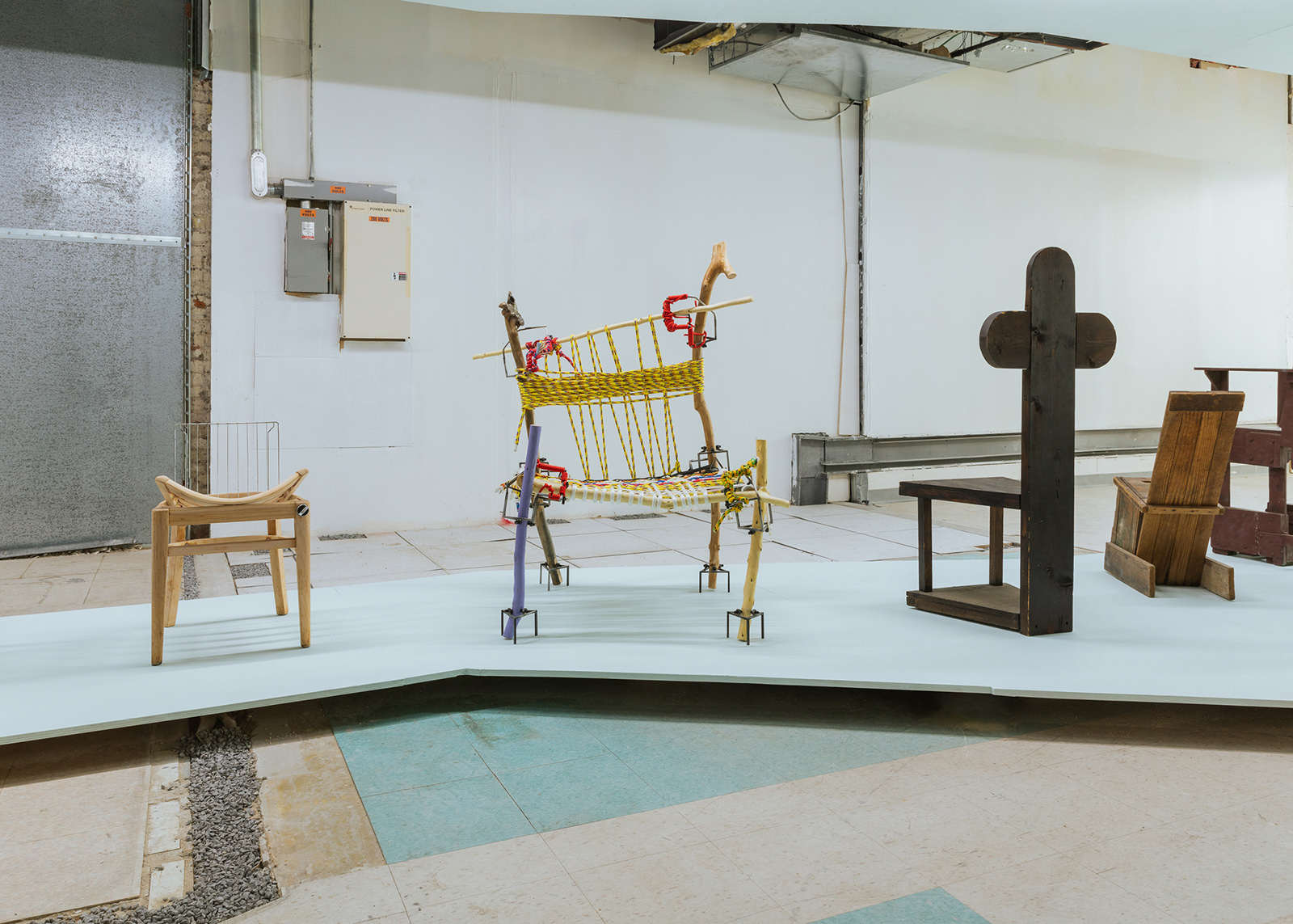 four chairs made of refuse on a platform in an industrial room