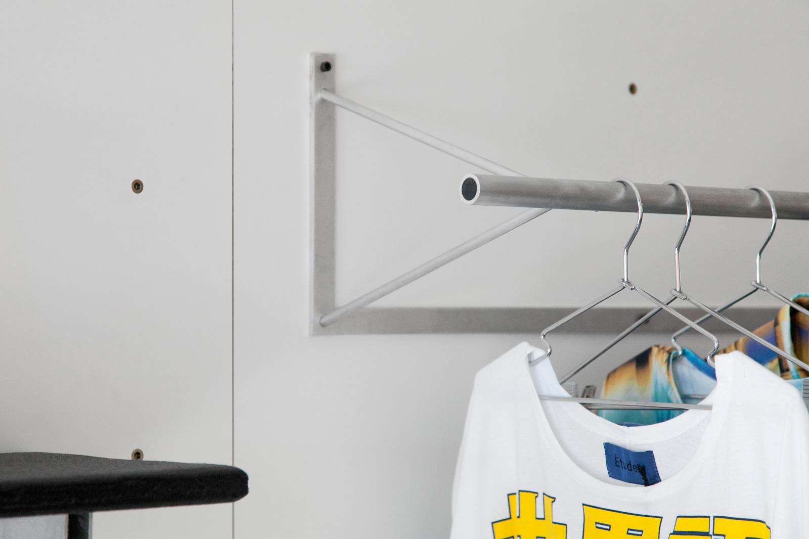 white wall with steel wall mounted clothes rack.