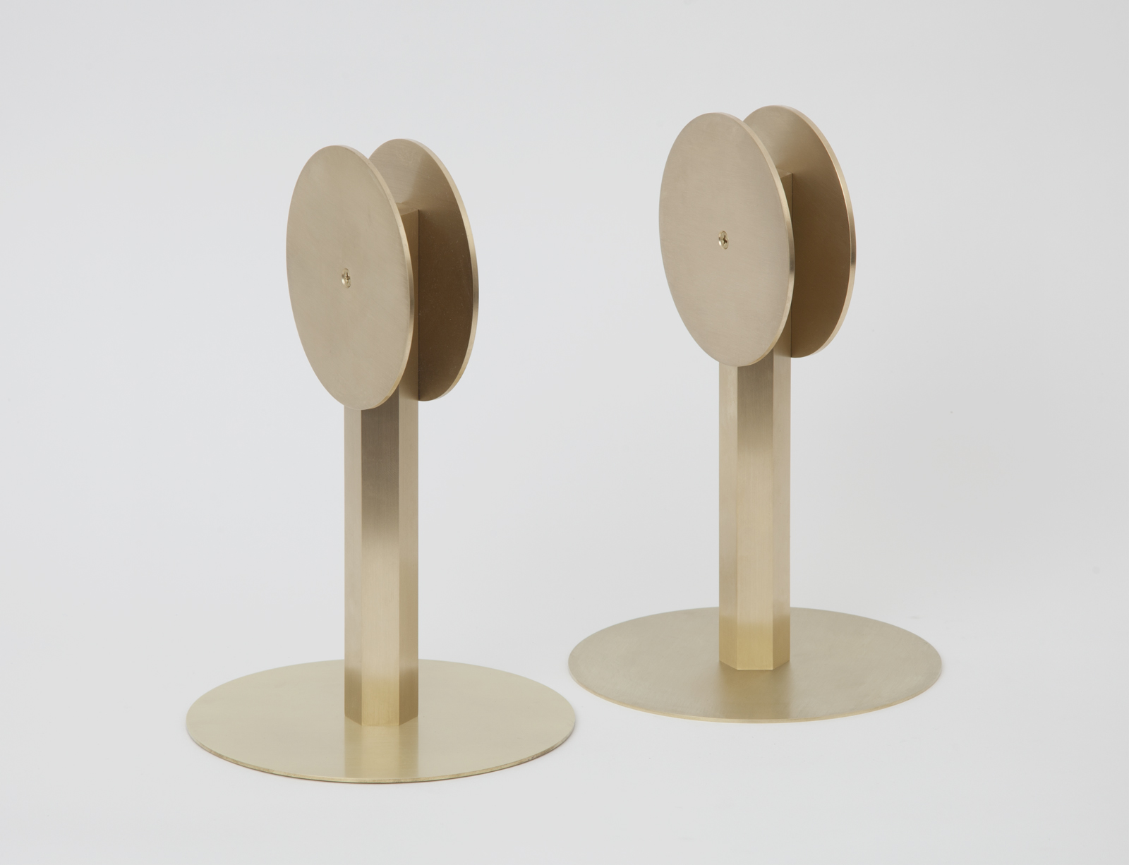 two brass circular disks on stands with round bases.