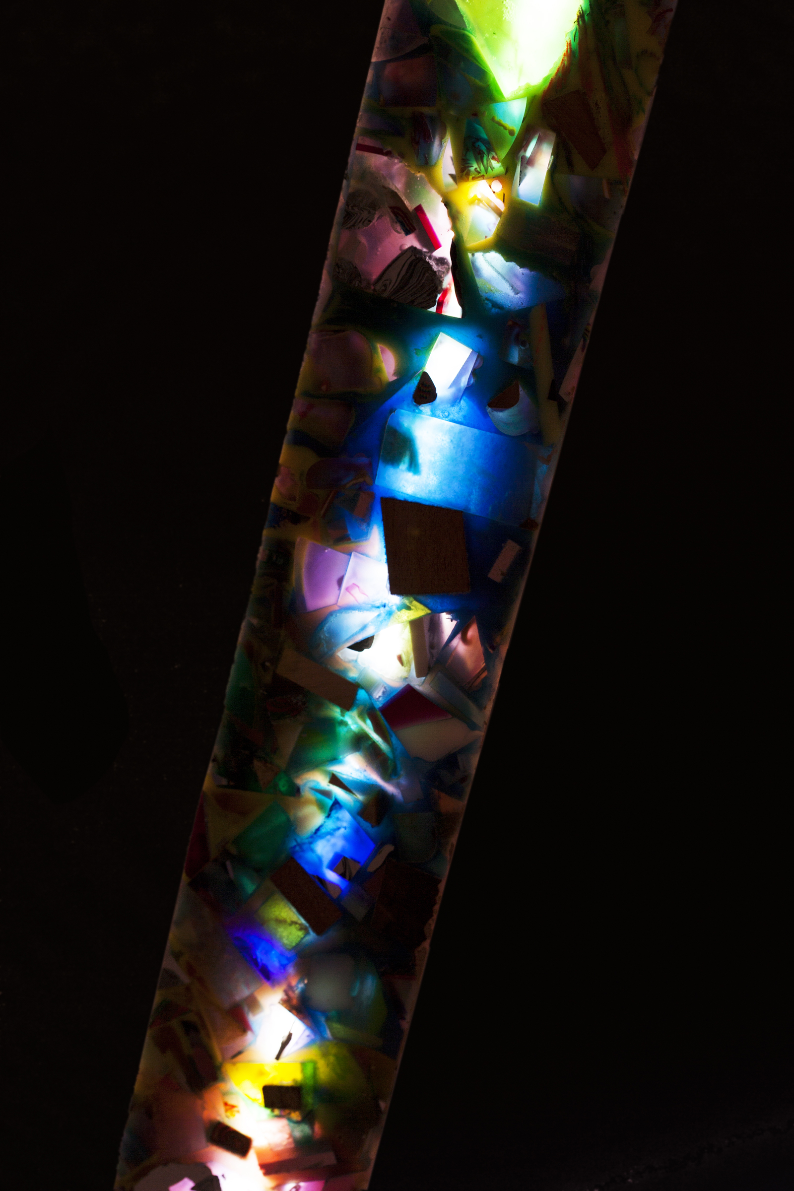 illuminated resin pillar in dark environment. glowing resin of various colors, blue, purple, green, yellow, red.