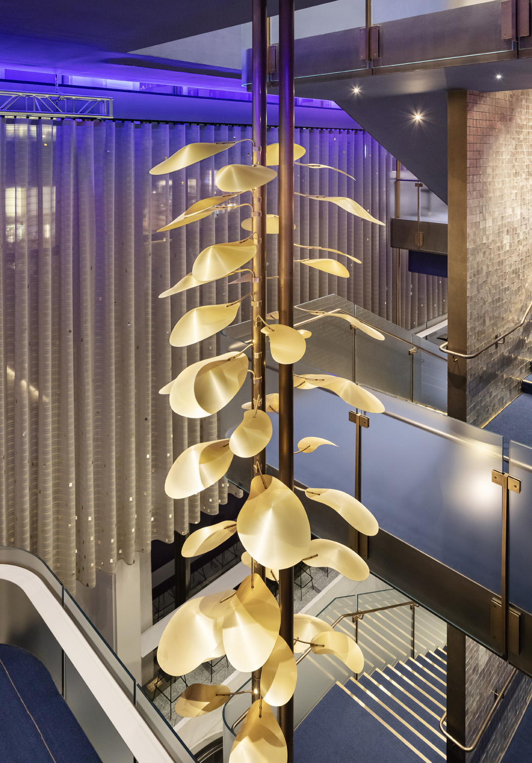 interior of david geffen hall with tall lighting installation consisting of gold tone petals