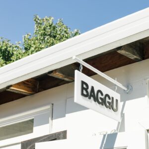 white building with sign reading "BAGGU" in black text.