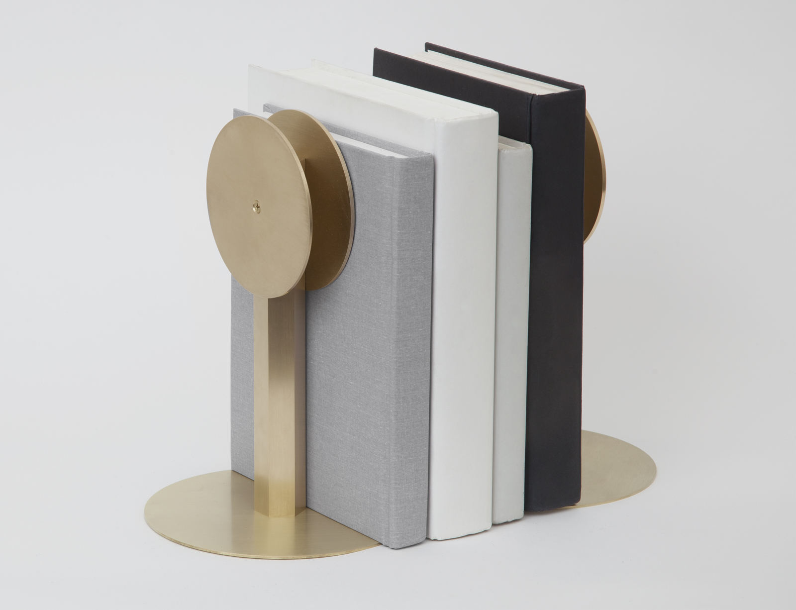 two brass circular disks on stands with round bases with books in between.