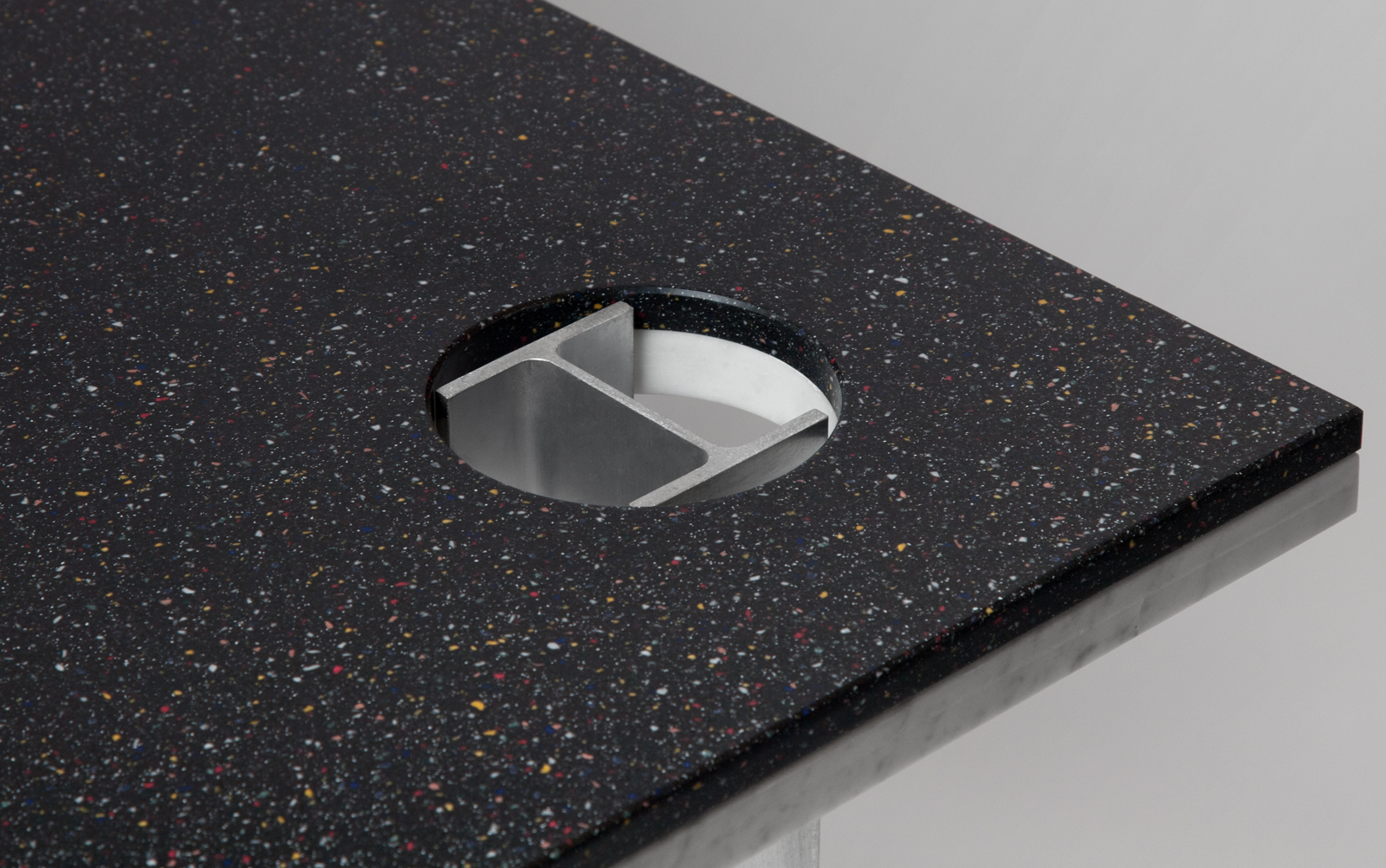 close up of black speckled Corian table top with aluminum I-beam base.