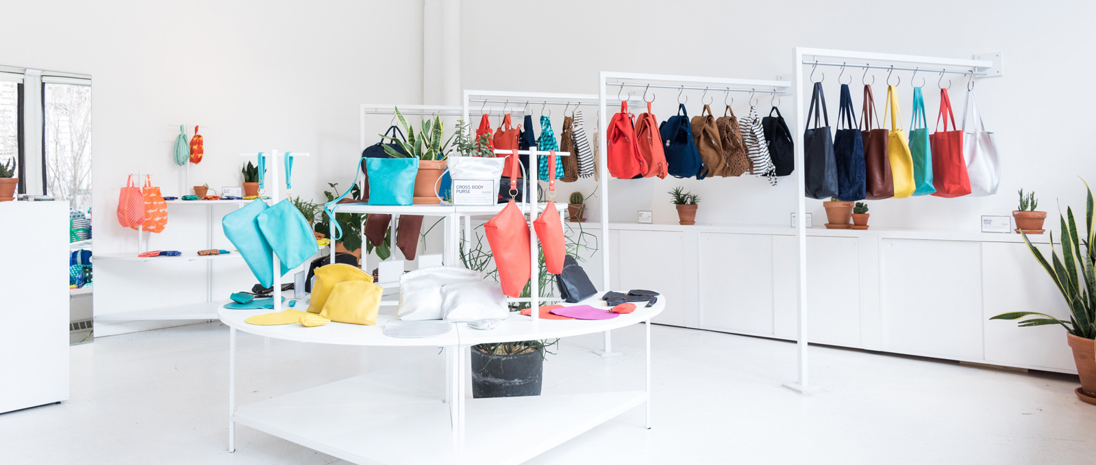 BAGGU store. multi level white shelving and bag handing rods.