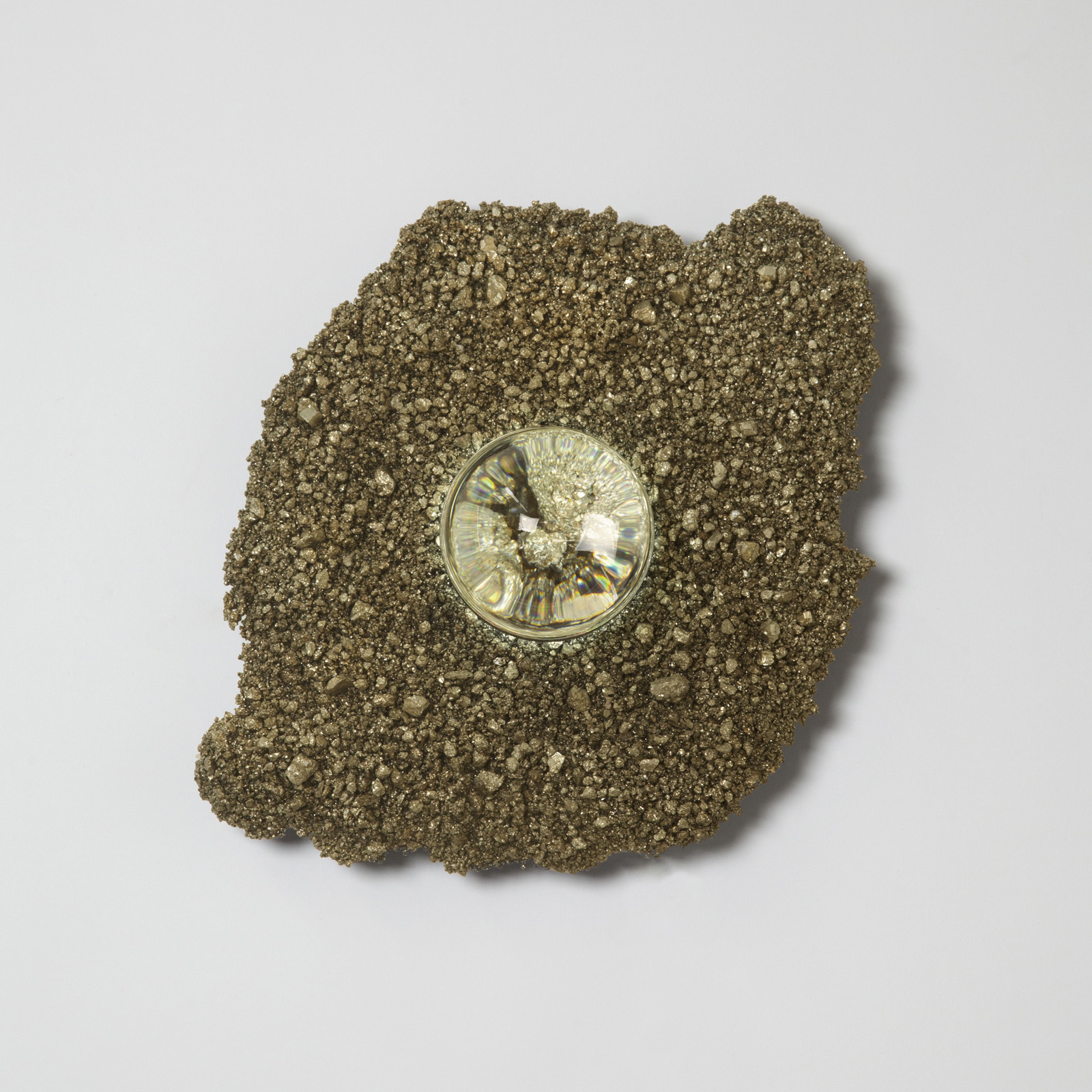 wall sconce in organic, irregular shape made of gold pyrite chunks. illuminated glass orb lens in center