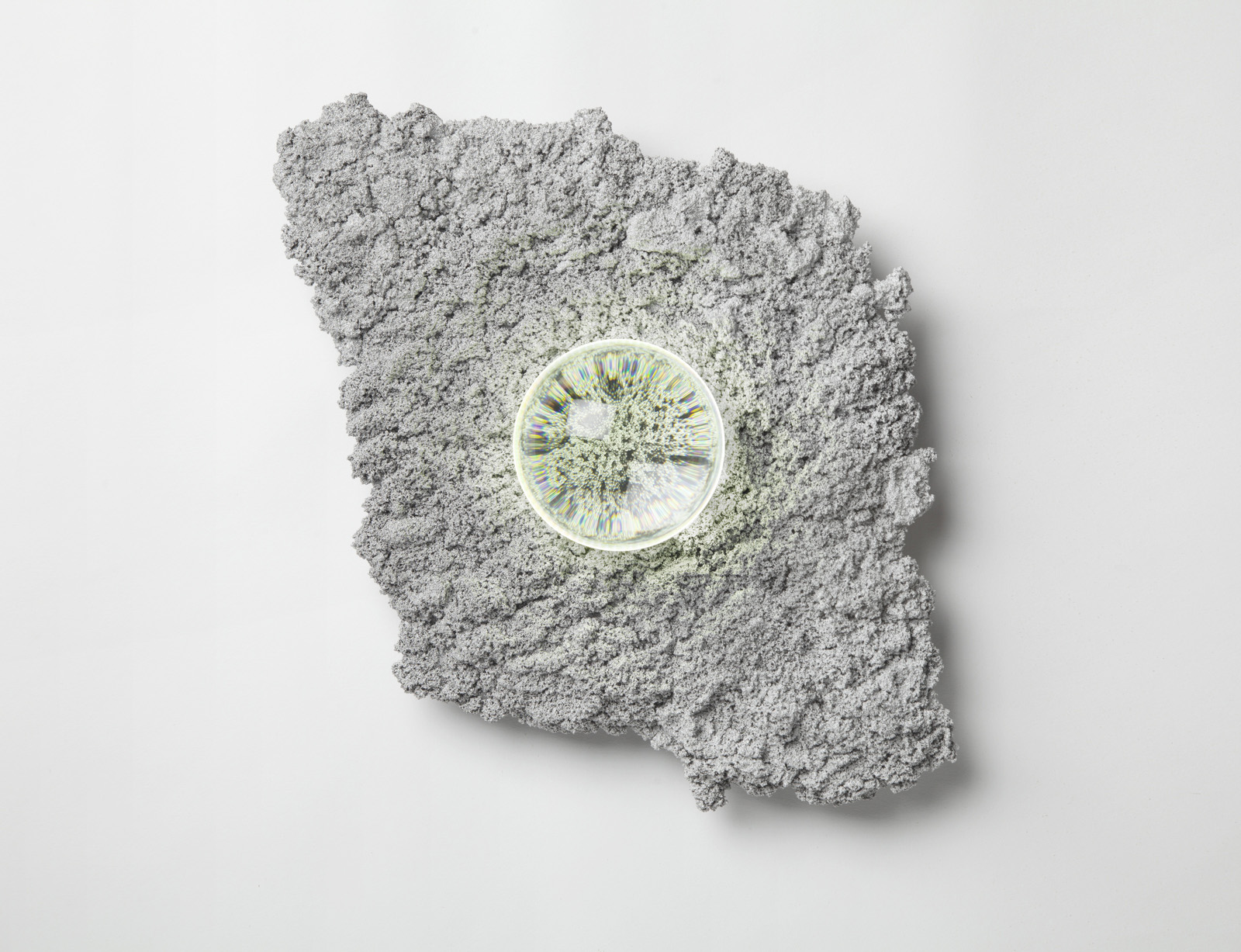 wall sconce in organic, irregular shape silver and rough textured. illuminated glass orb lens in center