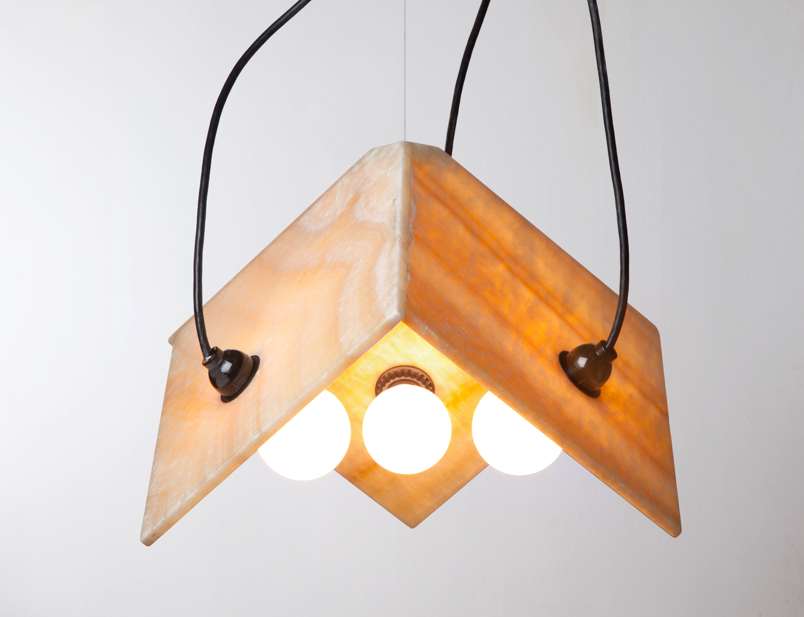 hanging light with three light bulbs held together by stone slices in a partial box formation.