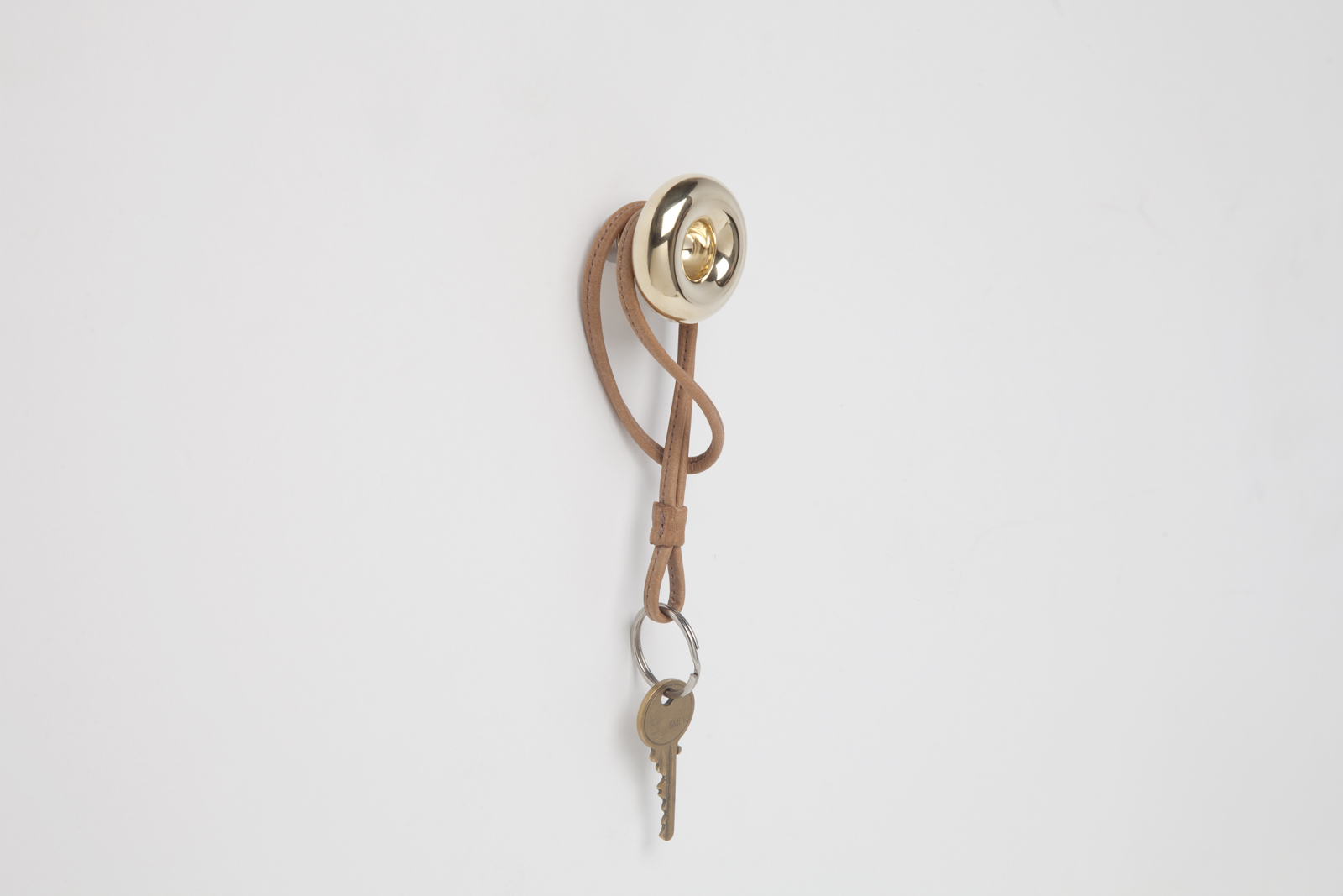 brass wall hook with donut shaped ring end and rod body with silver colored end cap and leather keychain hanging off..