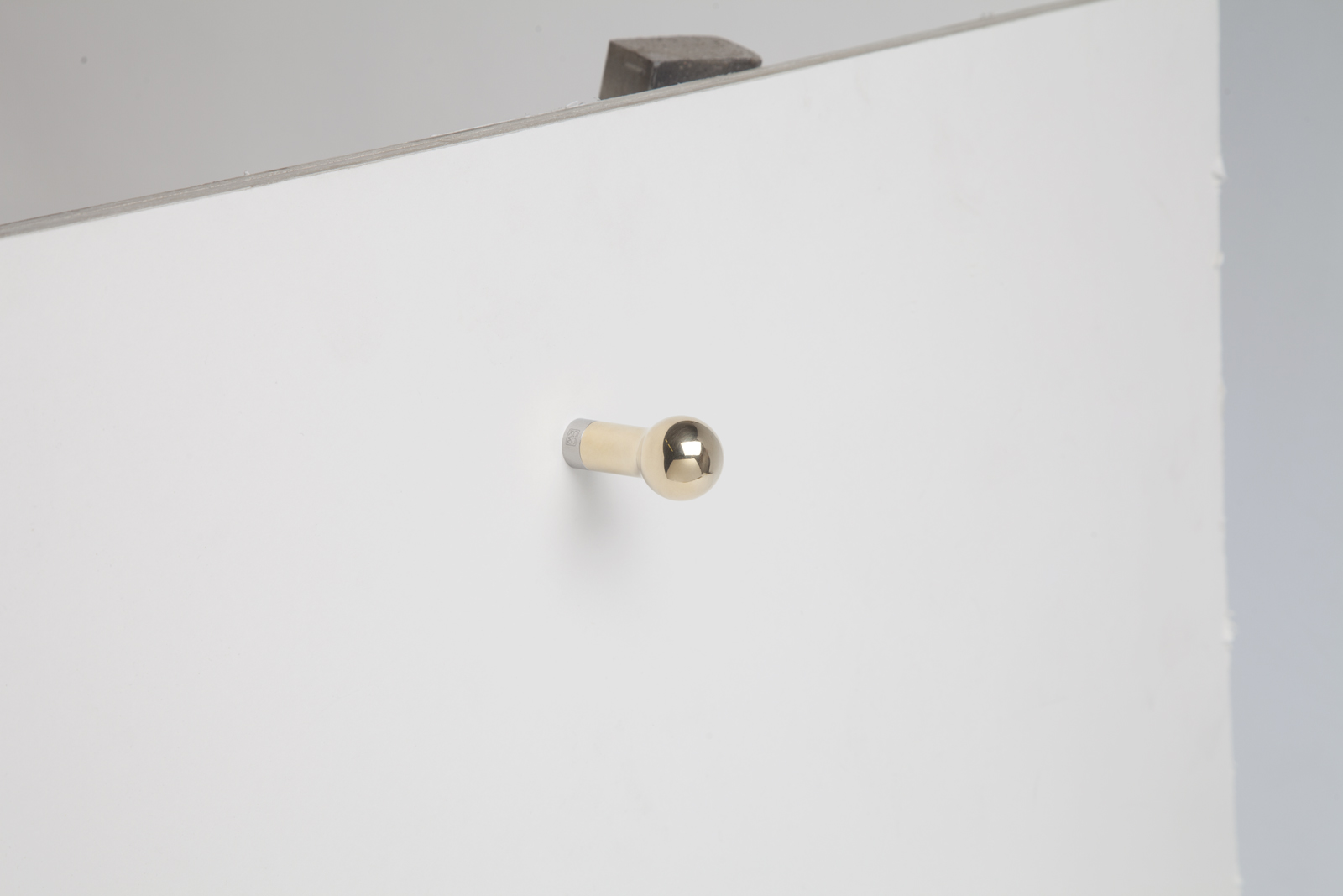 brass wall hook with sphere end and rod body attached to wall.