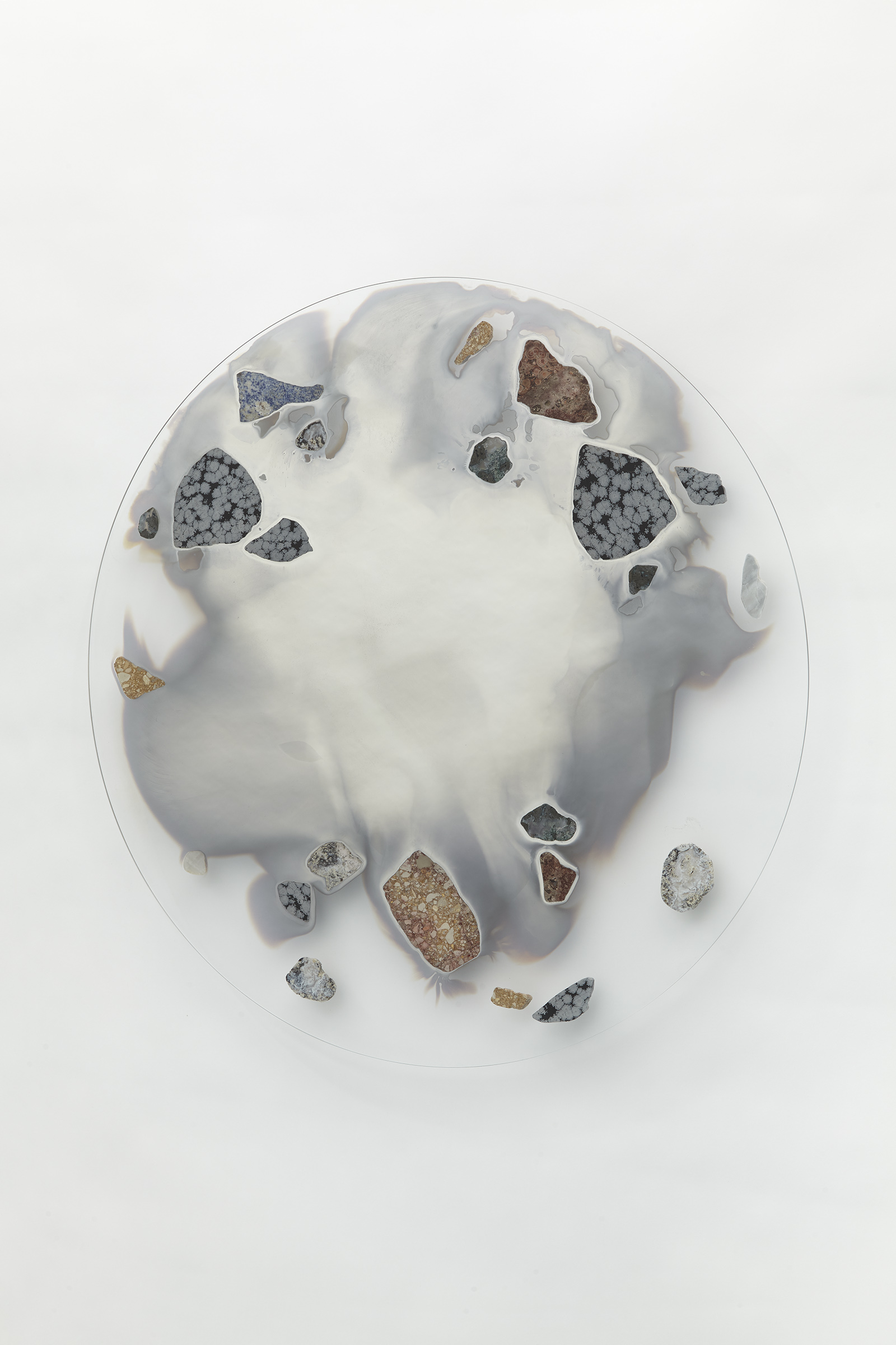 wall mounted circular glass with smoky mirror in center surrounded with various stone slices.