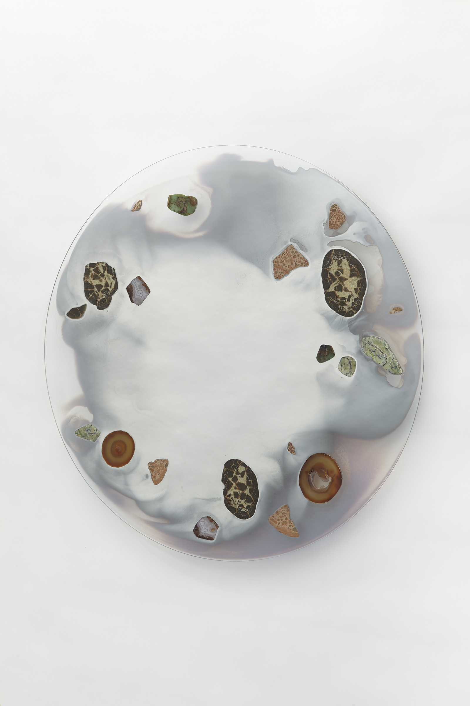 wall mounted circular glass with smoky mirror in center surrounded with various stone slices