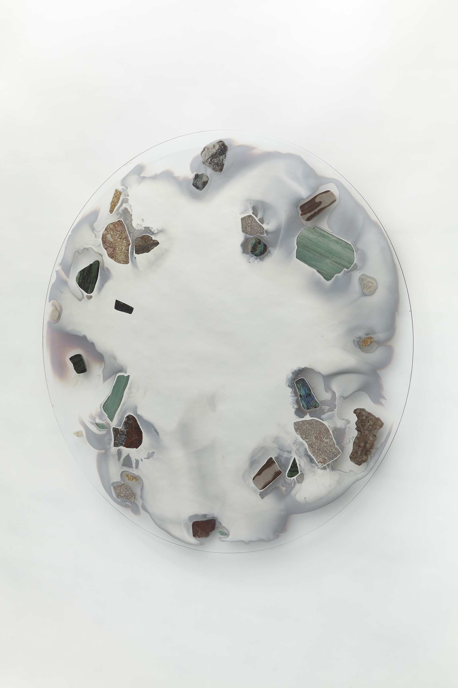 wall mounted circular glass with smoky mirror in center surrounded with various stone slices