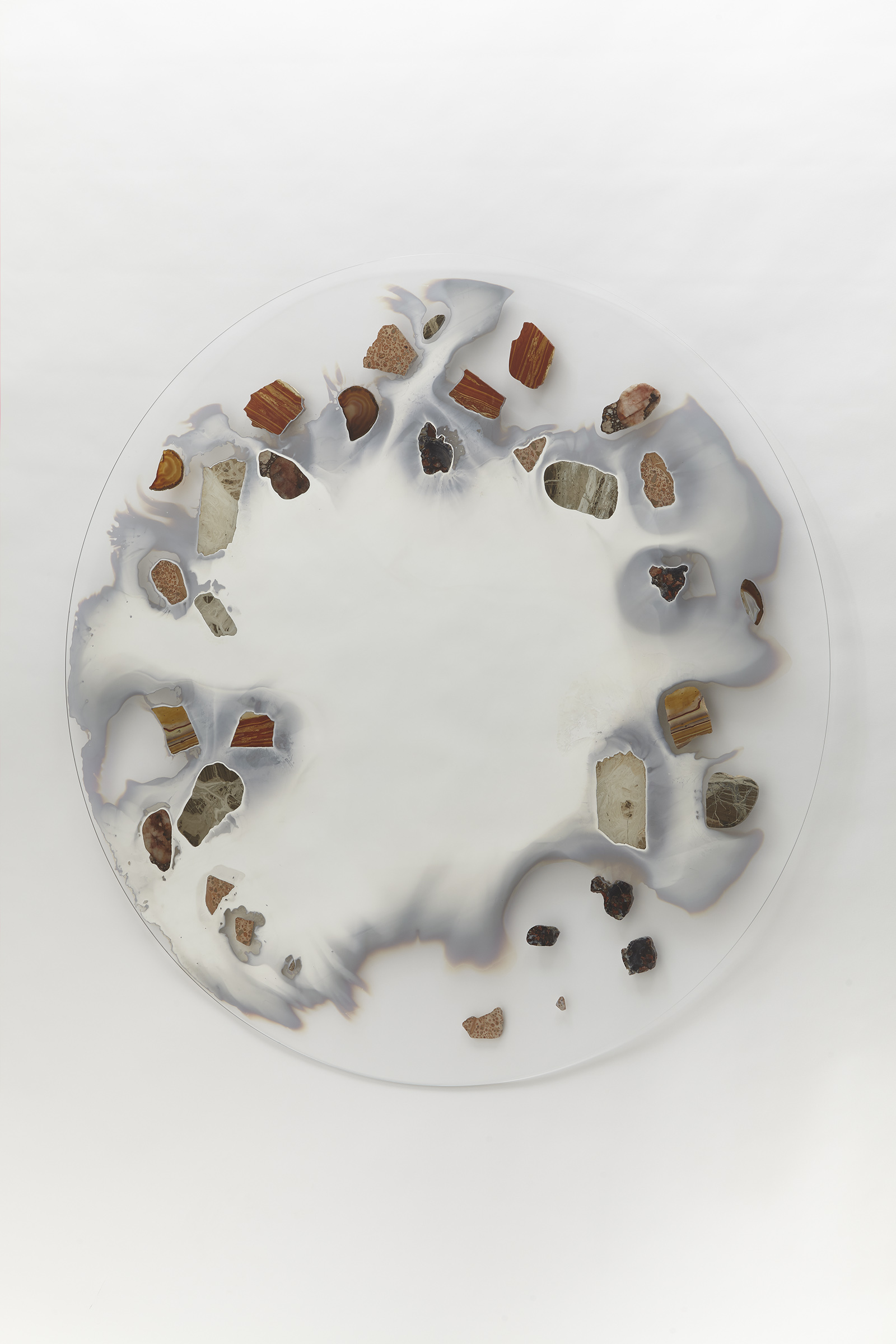 wall mounted circular glass with smoky mirror in center surrounded with various stone slices