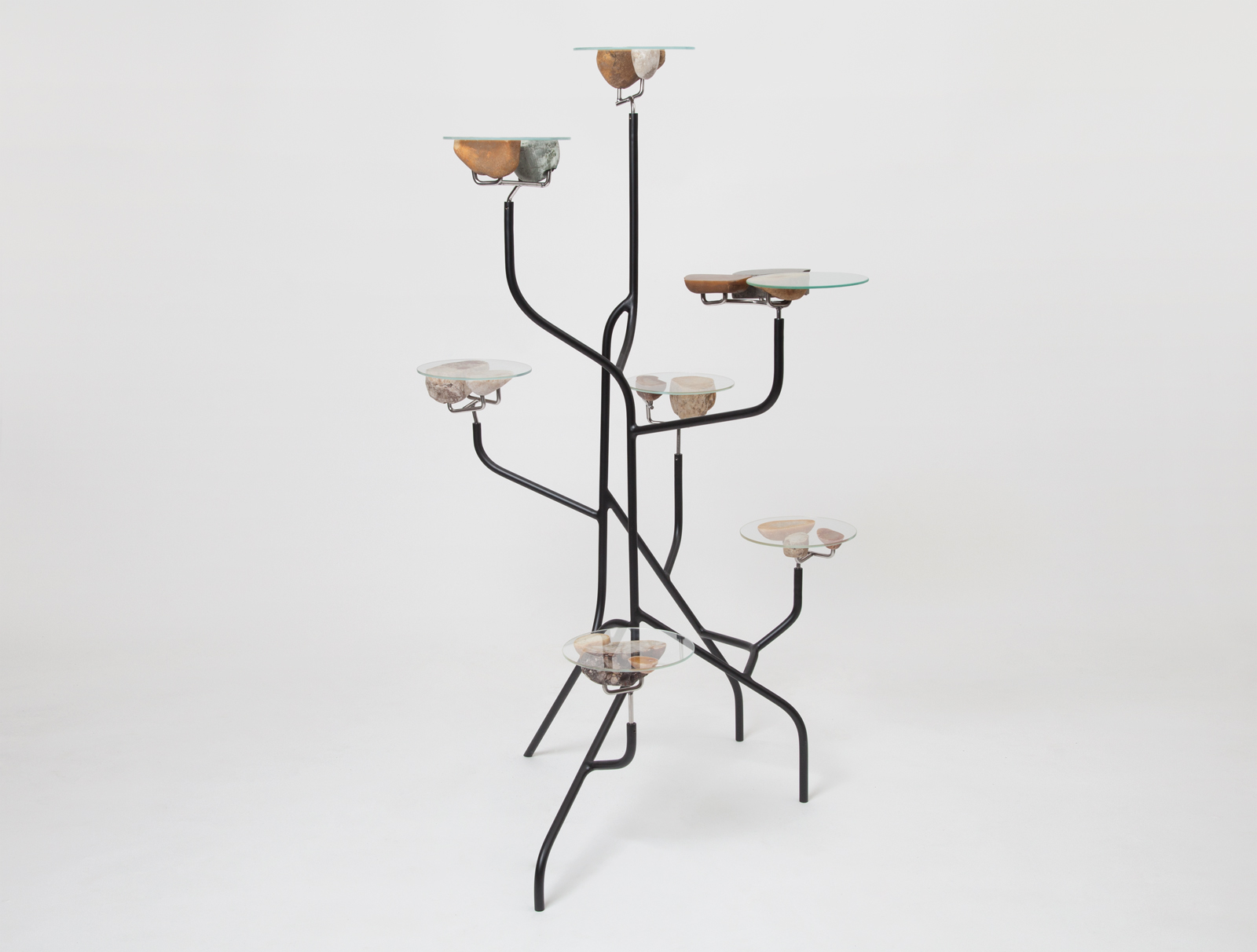 shelf with black steel base and multiple levels of various heights. each level is held up with a collection of stones cut in half and topped with a piece of glass.