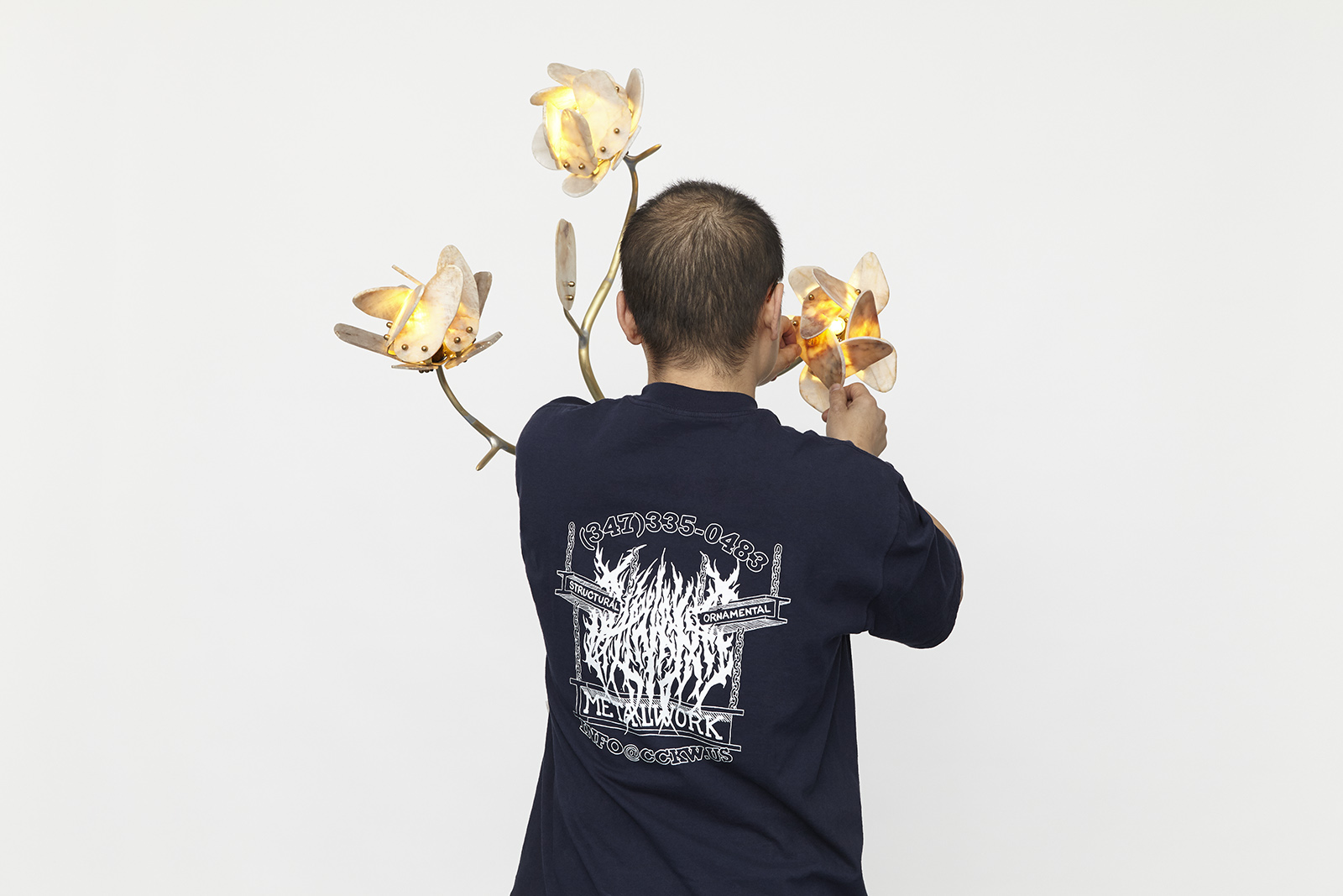 man wearing navy blue t shirt with white graphics in front of stone rose sconce.