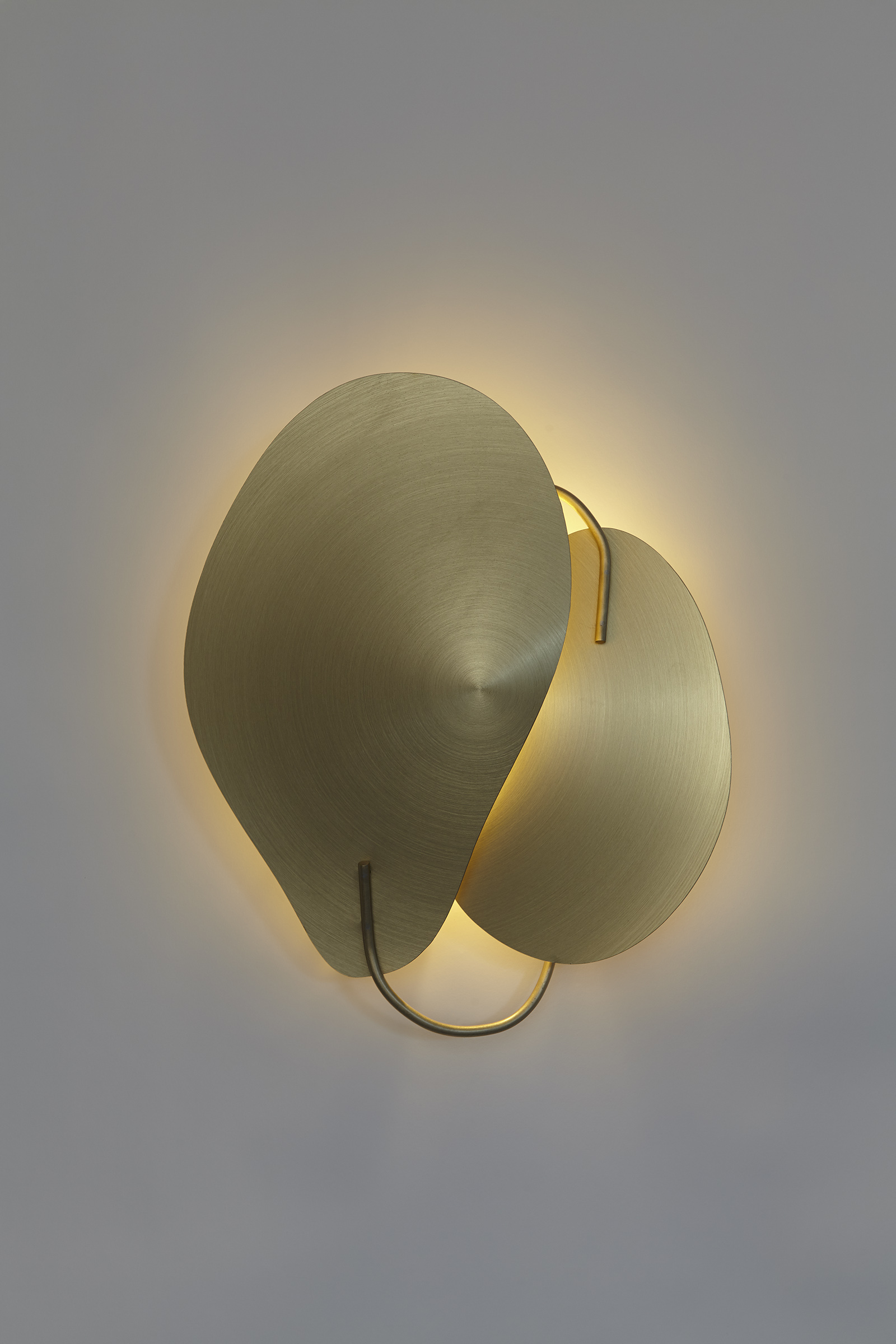 front view of two gold color petal shaped metal pieces overlapping wall mounted sconce.