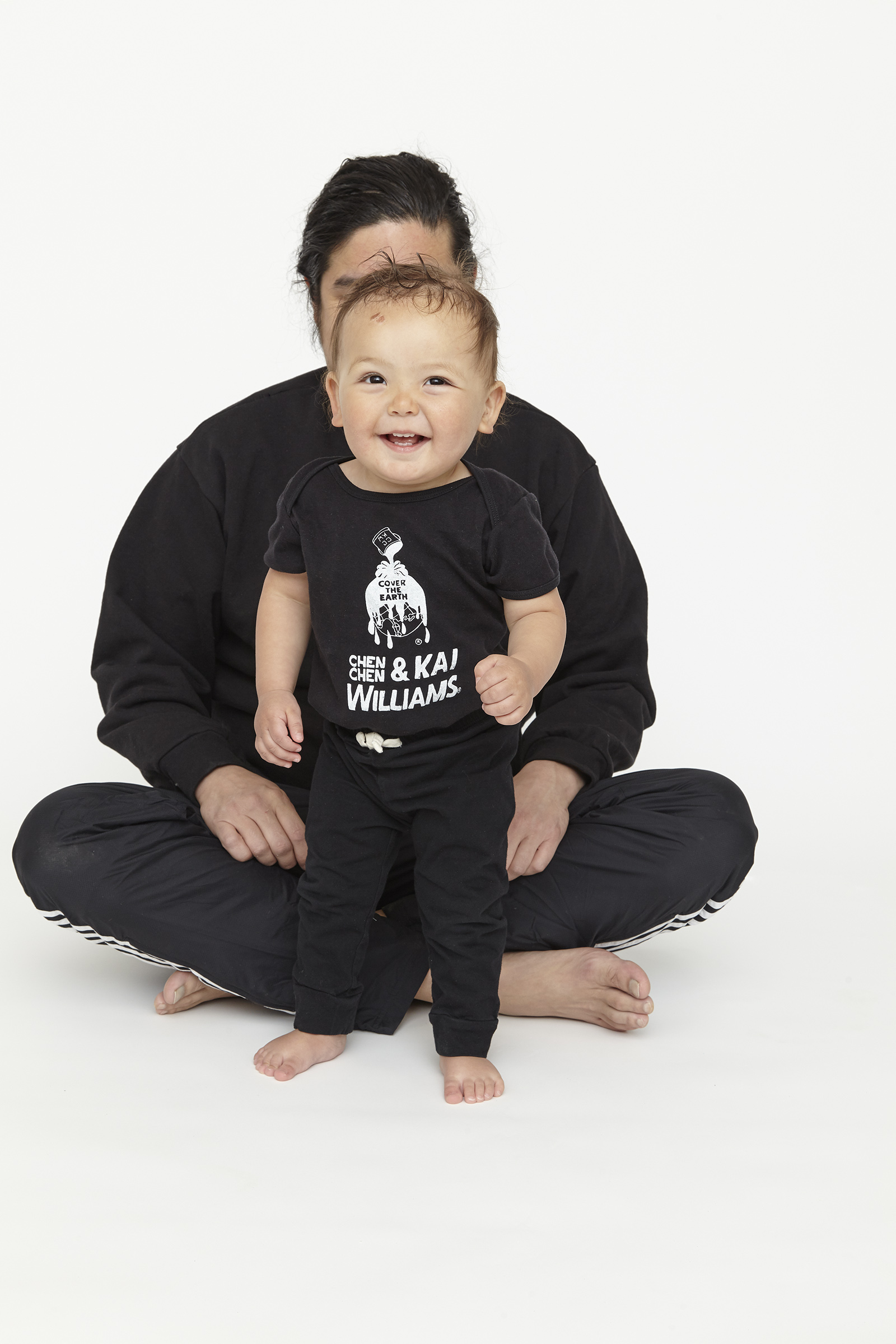 child wearing black onesie with white graphics in front of man with black sweatshirt and white graphics