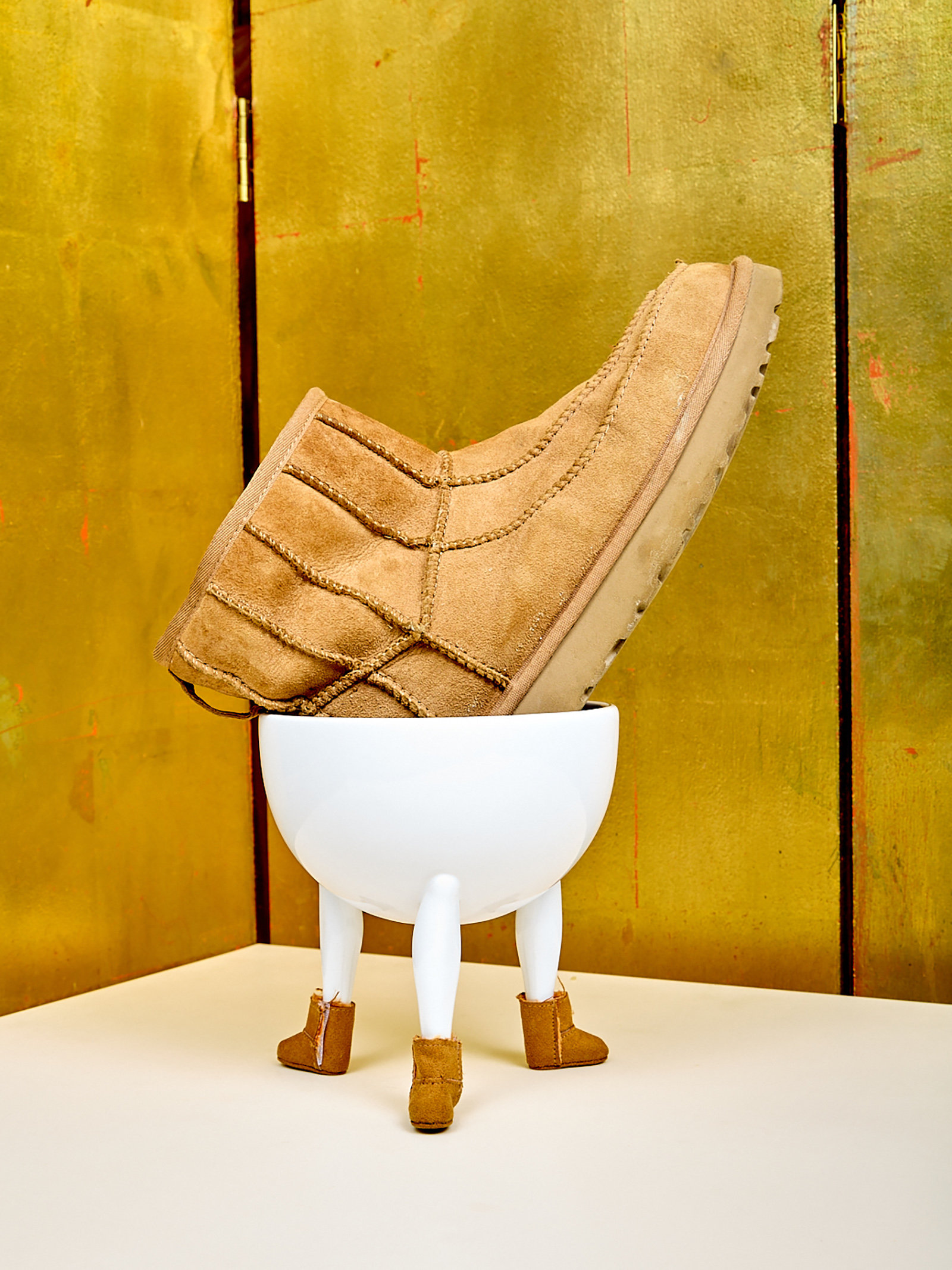 ceramic bowl with a suede boot inside also wearing mini suede boots