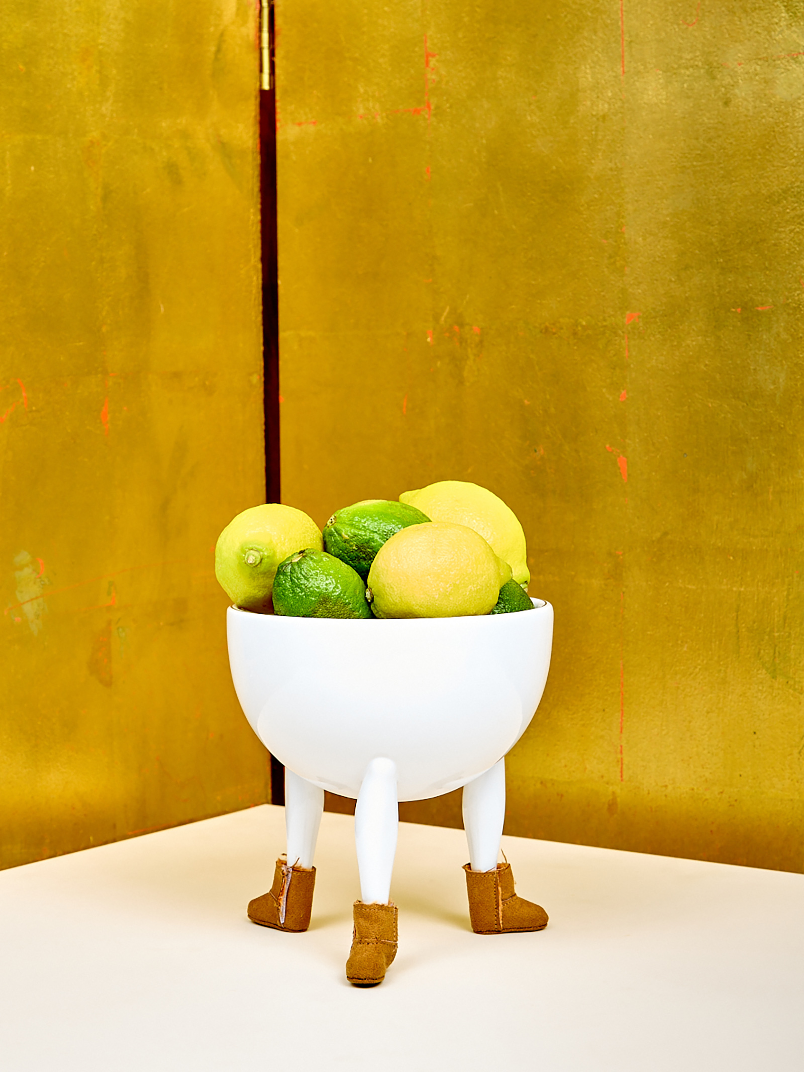 ceramic bowl with legs wearing miniature suede boots with limes inside the bowl