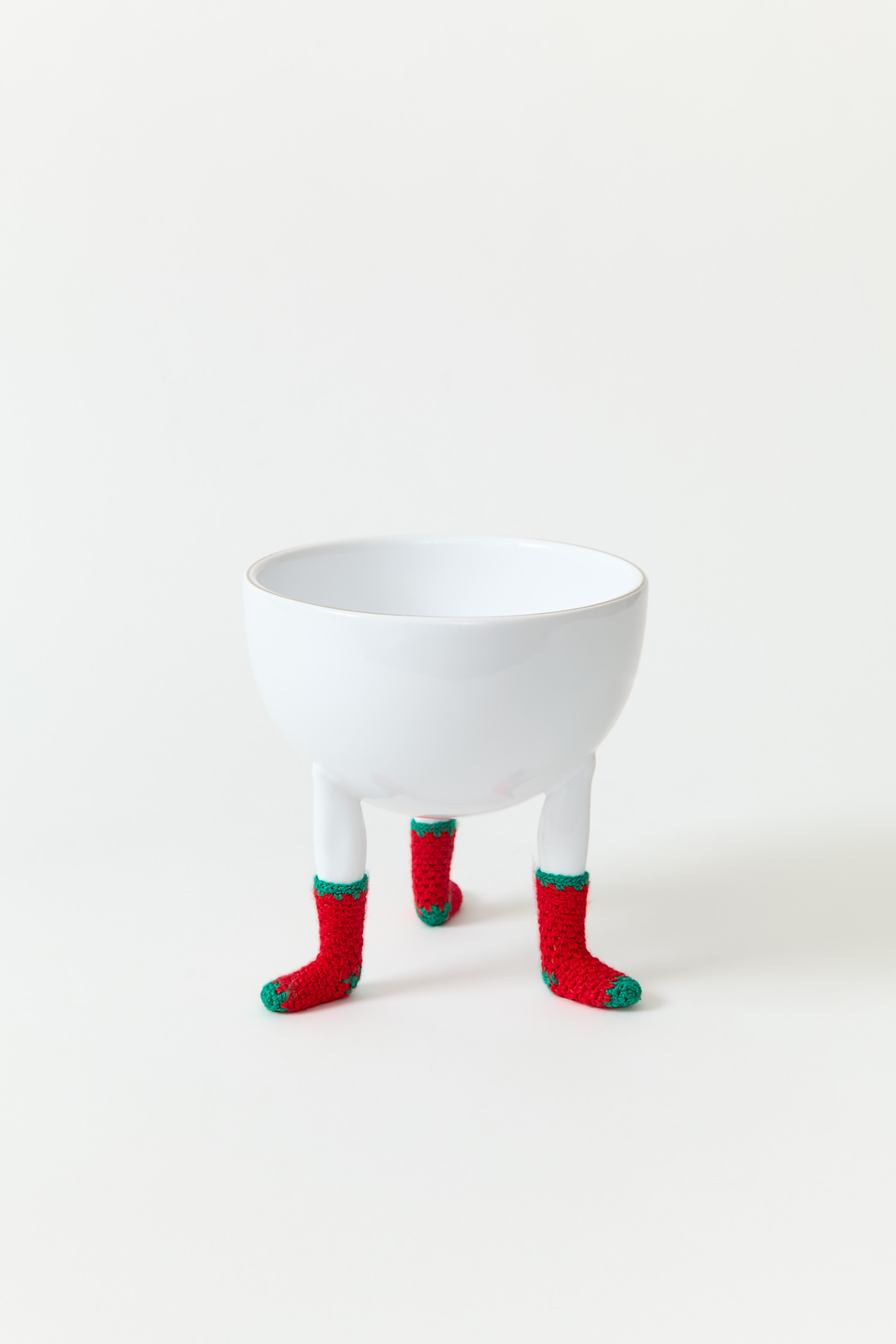 A bowl with three figurative legs wearing miniature christmas socks