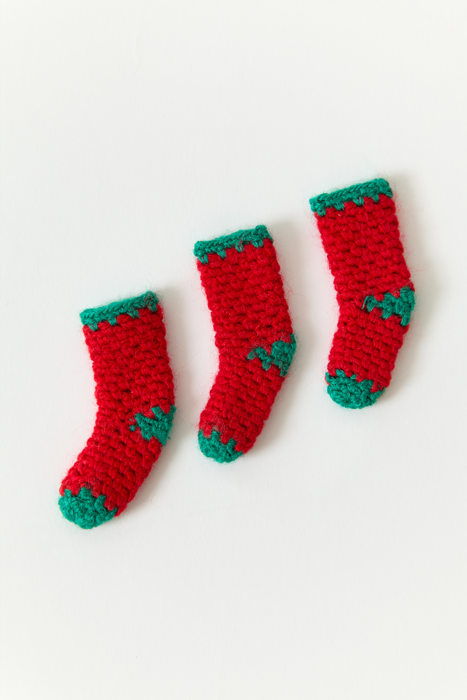 Three miniature crocheted socks lined up in a row diagonally