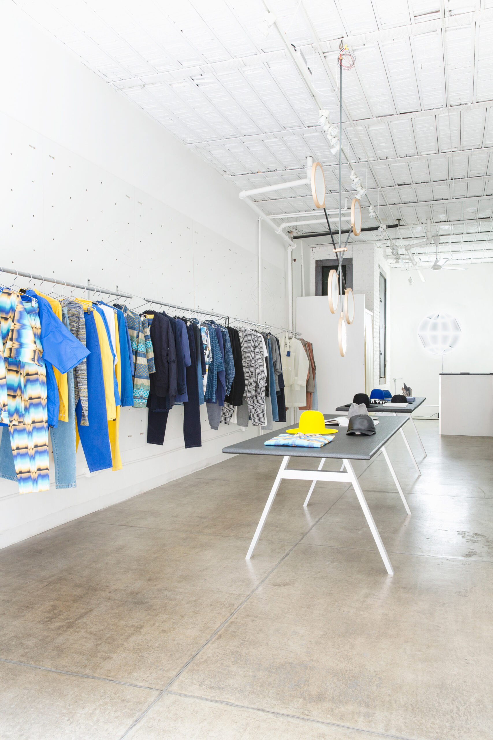 pop up shop with concrete floors and white interior, rack of clothing and table with goods.