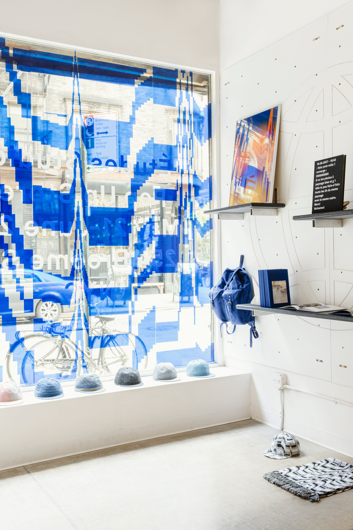 pop up shop with blue marbled window design and window display with hats, wall shelves.