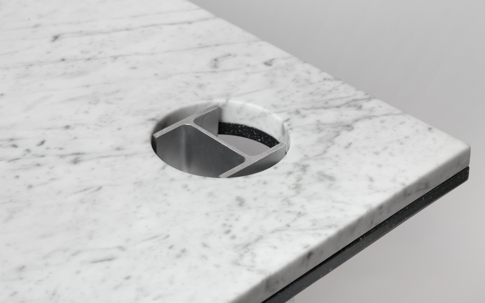 close up of White Carrara table top with aluminum I-beam base.