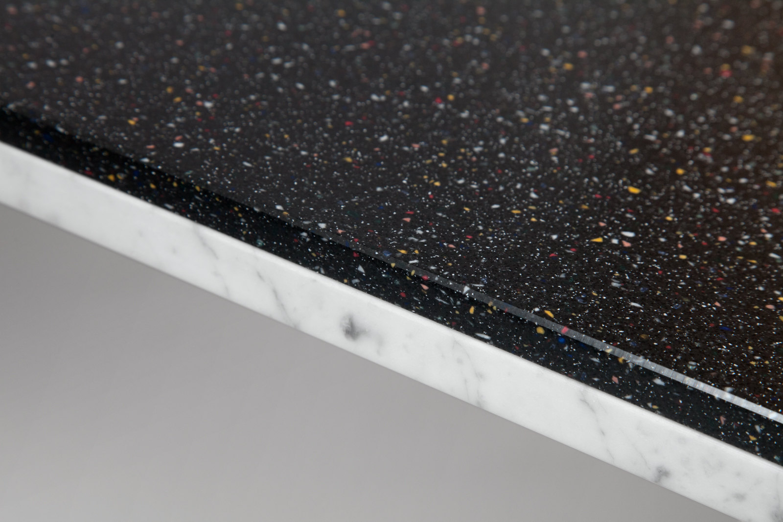 close up of double sided White Carrara and black speckled Corian table top.