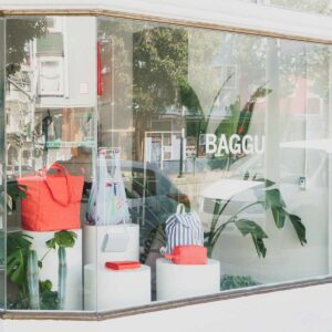 BAGGU storefront window display with tiered white structures and colorful bags.