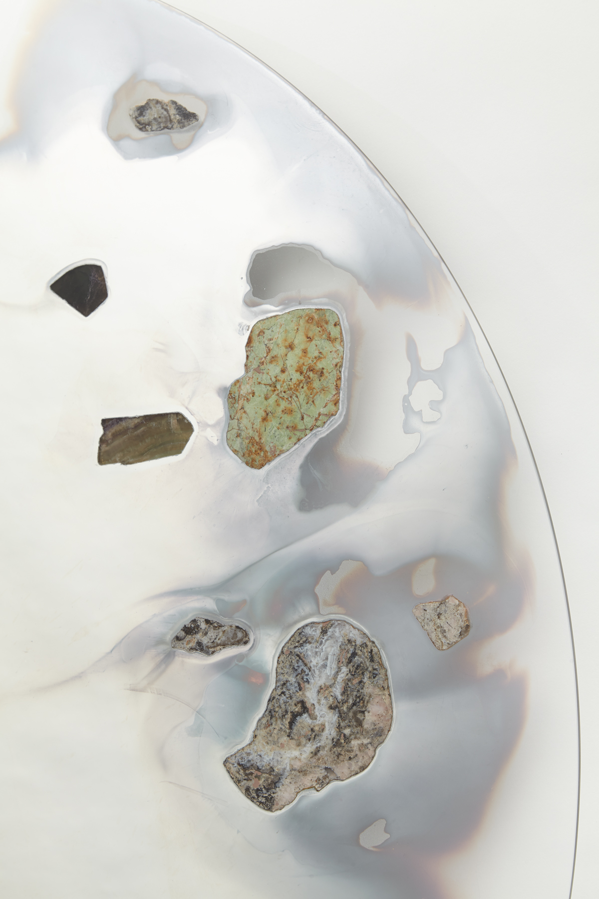 wall mounted circular glass with smoky mirror in center surrounded with various stone slices