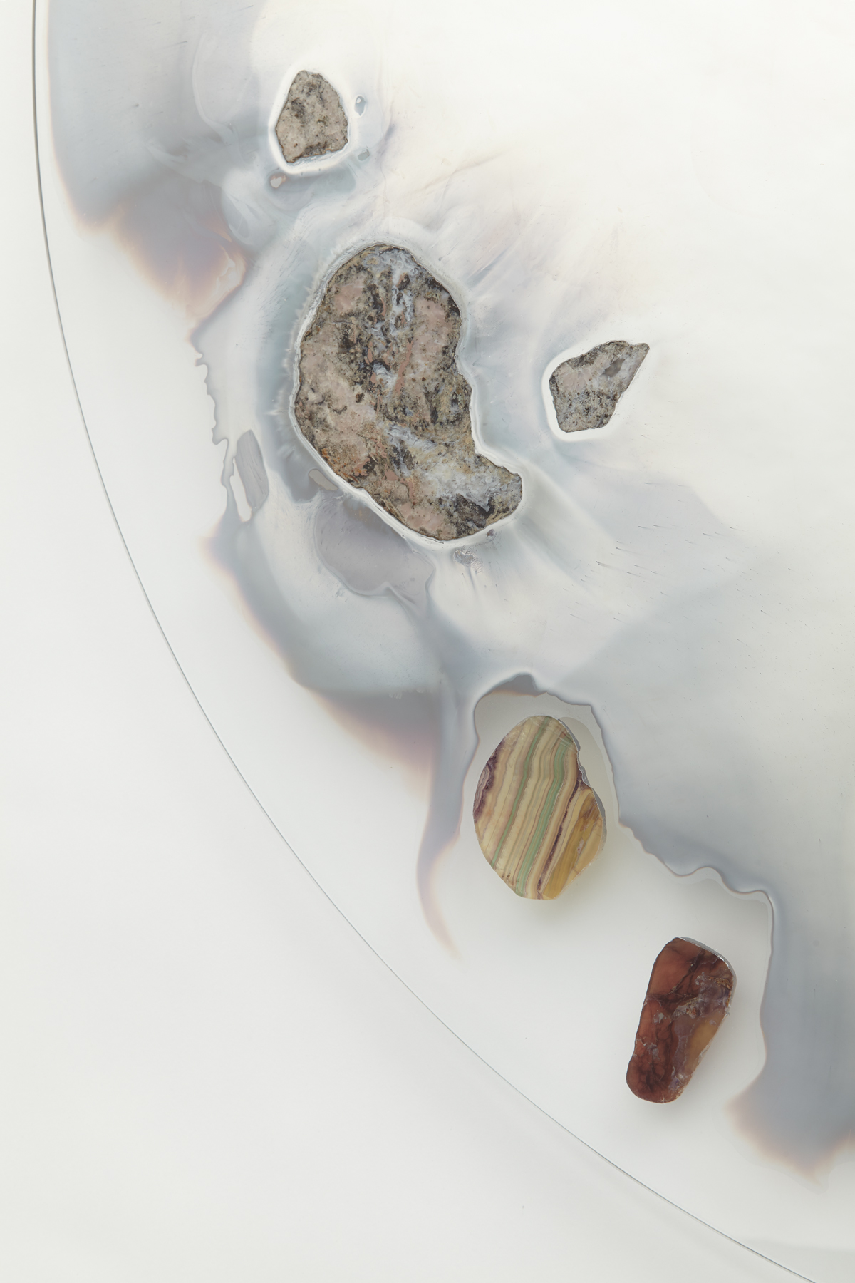 wall mounted circular glass with smoky mirror in center surrounded with various stone slices