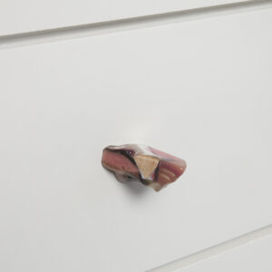 A colorful resin drawer pull on a white drawer front