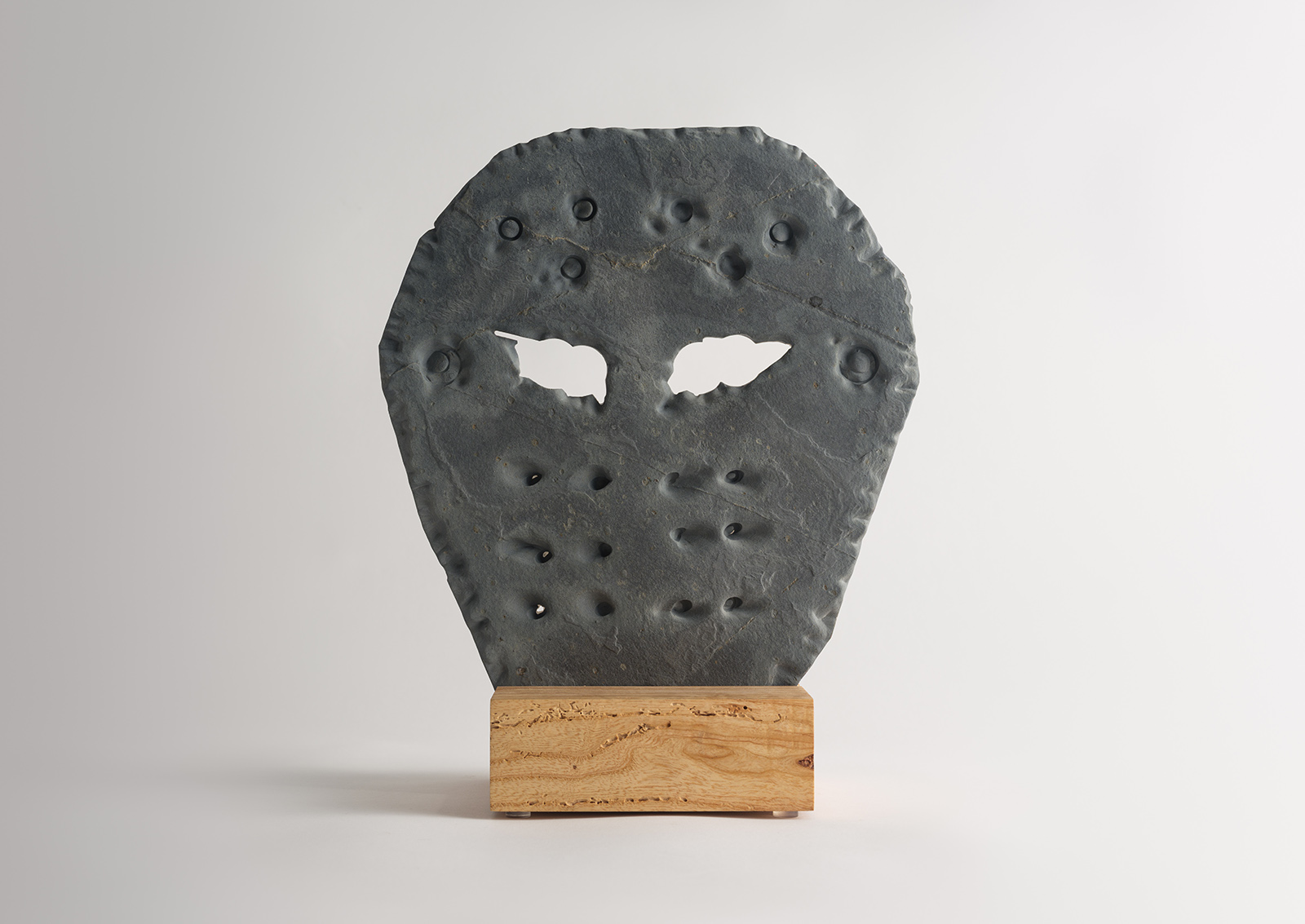 stone hockey mask carved from slate on a wood base