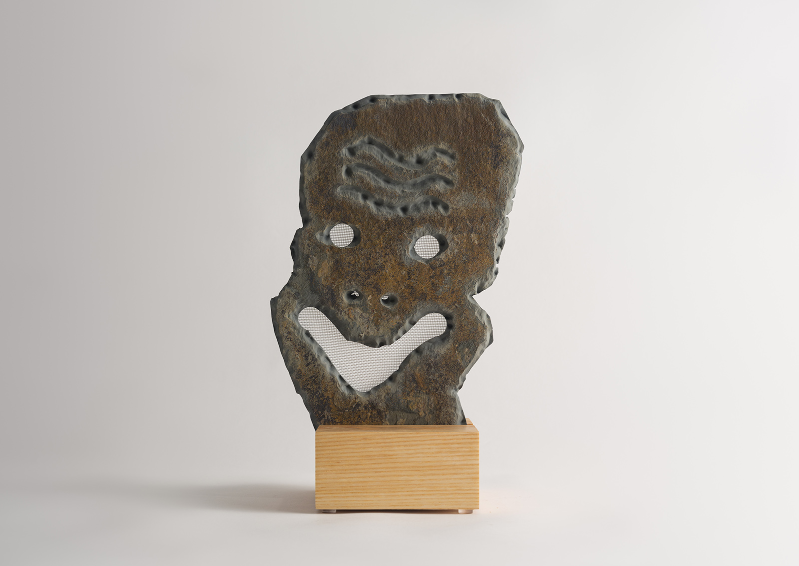 stone mask carved from slate on a wood base