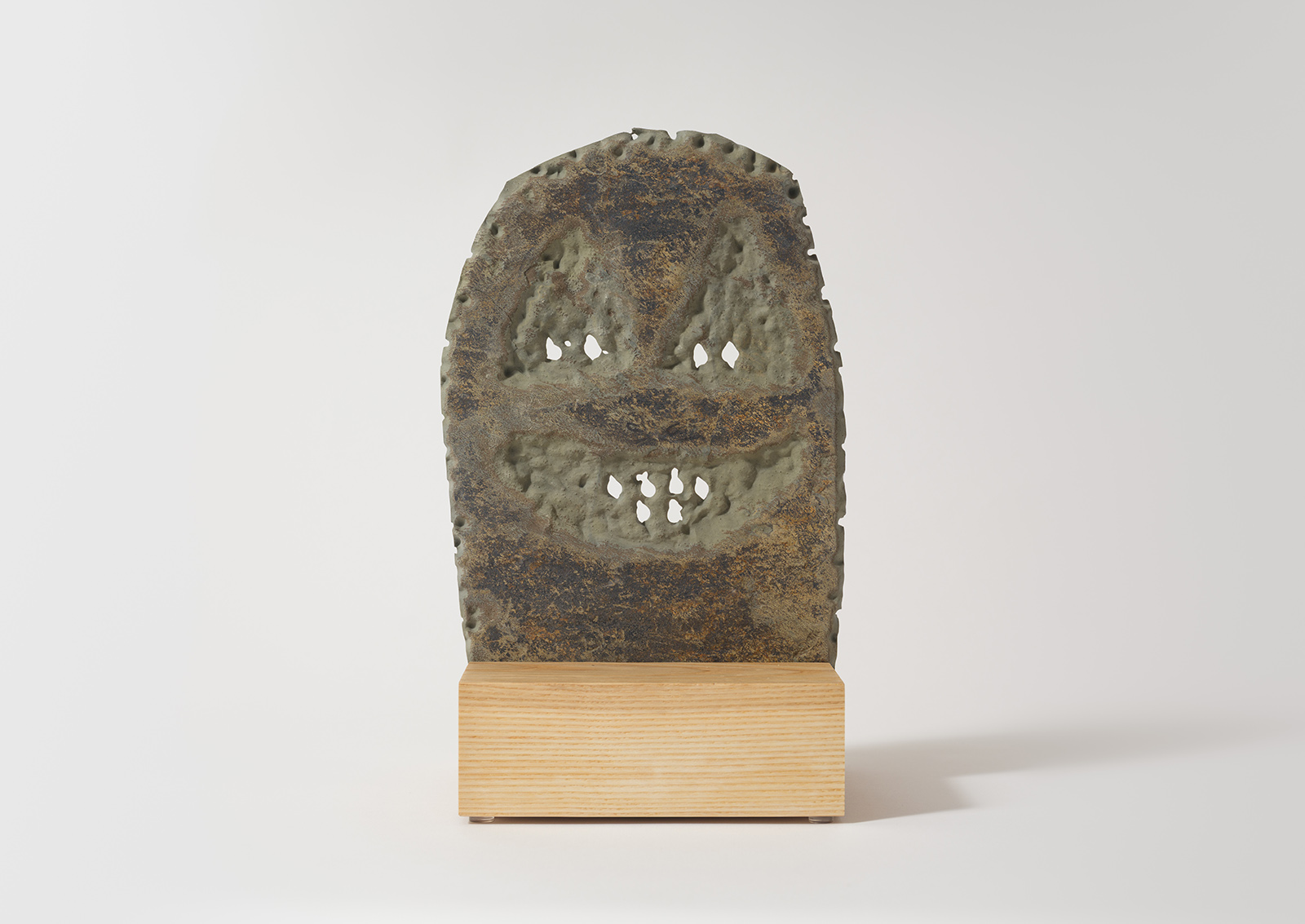 stone mask carved from slate on a wood base
