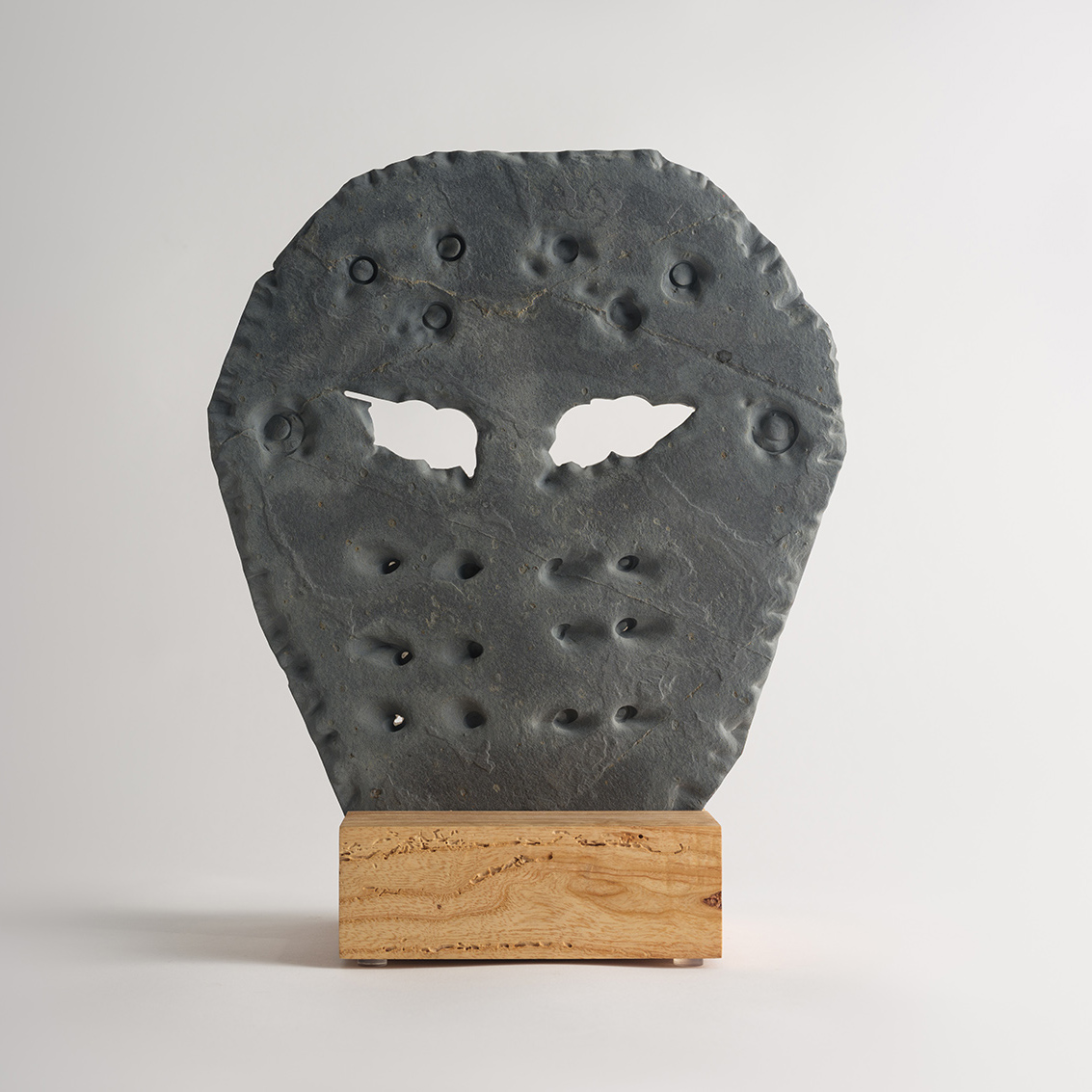 stone hockey mask carved from slate on a wood base