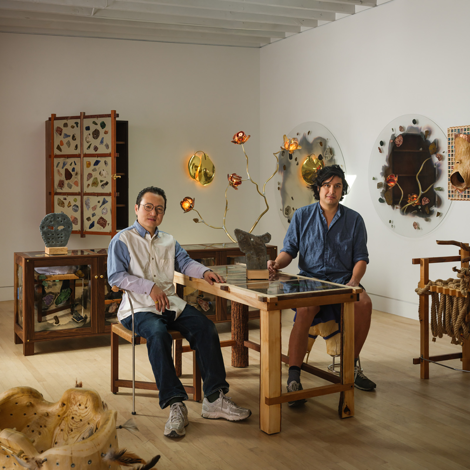 two people sitting on either side of a desk with furniture all around them