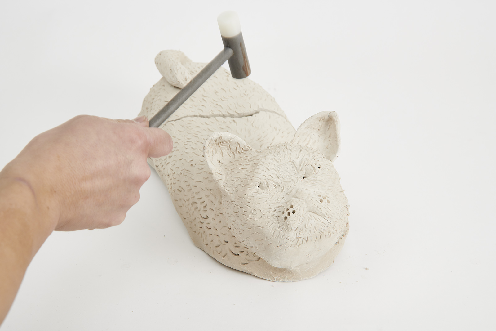 clay cat with hammer over it