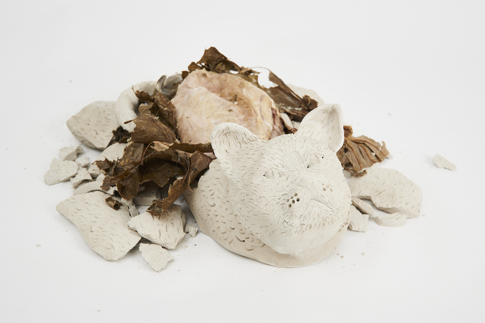 clay cat smashed open with lotus leave inside, also open, revealing rabbit meat inside